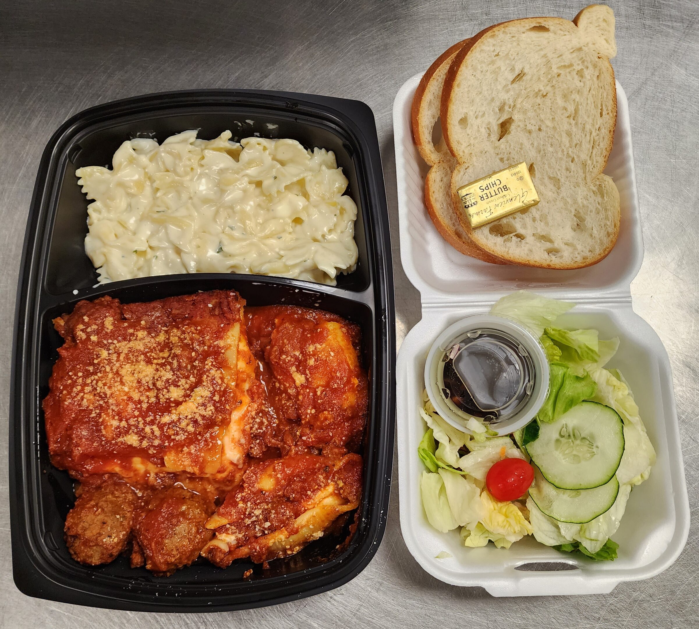 Takeout lasagna meal with salad and bread